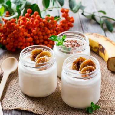 Ahşap bir masa üzerinde muz ile yoğurt. Sağlıklı kahvaltı.