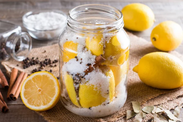 Limones conservados con sal en una tabla de madera con jugo de limón y especias — Foto de Stock
