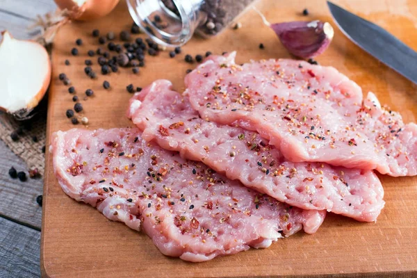 Tenderization of fresh pork steak on wooden chopping board on wooden desk — Stock Photo, Image