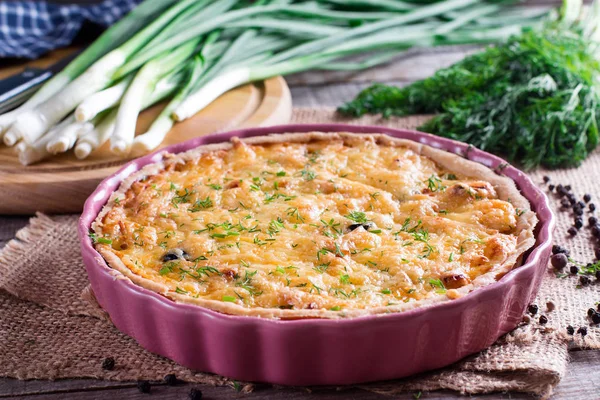 Französische Zwiebelkäse-Quiche oder Pastete in einer mit Petersilie bestreuten Auflaufform, mit Zutaten auf Schneidebrett — Stockfoto