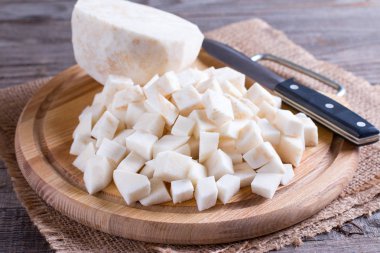 Hafif ahşap arka plan ağaç kesme tahtasında tüm kereviz kök yarısı ile küçük parçalara kesmek kök kereviz