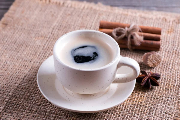Xícara de café, paus de canela na mesa de madeira no fundo marrom — Fotografia de Stock