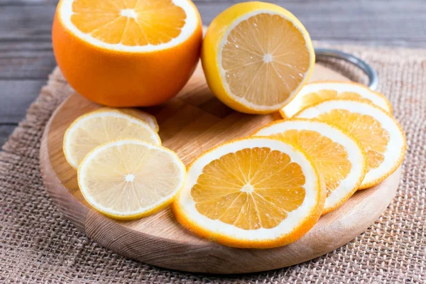 Rodajas de naranja sobre tabla de cortar con limón — Foto de Stock