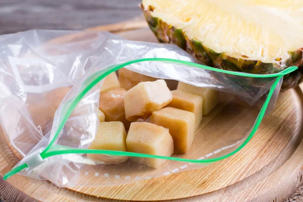 Frozen pineapple cubes in a bag of chopping board — Stock Photo, Image