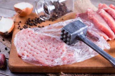 Ahşap masa üzerinde bir kesme tahtası üzerinde ham pirzola