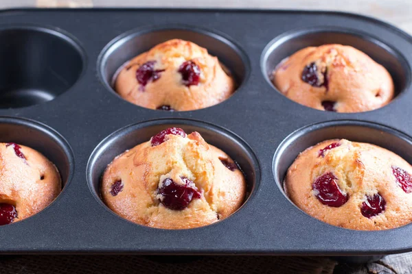 Homemade muffins with cherry in a baking form on a wooden background Stock Photo