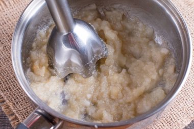 Blender ve armut bir tencerede. Çocuk püre hazırlanıyor