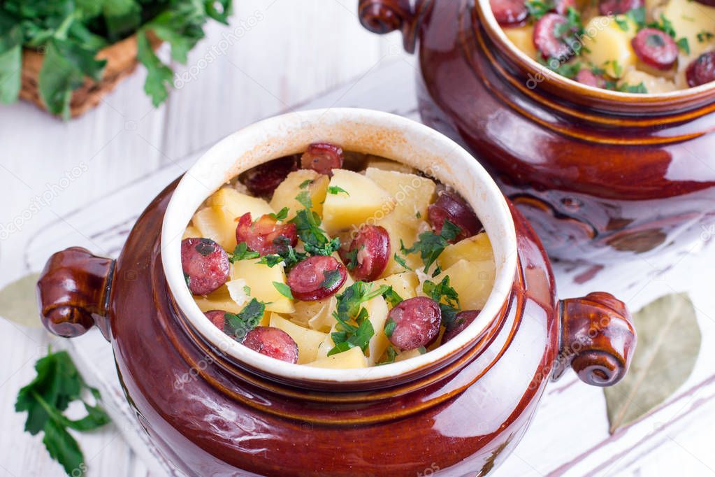 Hot potato goulash with bacon and Vienna sausages served in a ceramic bowl with on a table