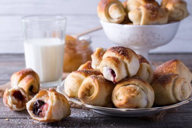 Rugelach with jam filling on plate with milk on wooden background - a traditional European pastry clipart