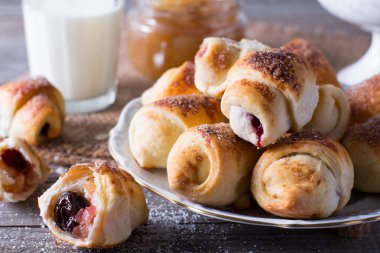 Rugelach with jam filling on plate with milk on wooden background - a traditional European pastry clipart