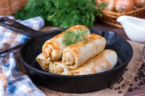 Crepes stuffed with minced meat and rice in a frying pan on a wooden table — Stock Photo, Image