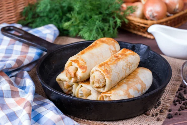 Crepes stuffed with minced meat and rice in a frying pan on a wooden table — Stock Photo, Image