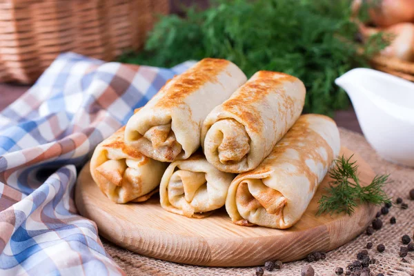 Thin pancakes with fillings with dill on a cutting board on a wooden table — Stock Photo, Image