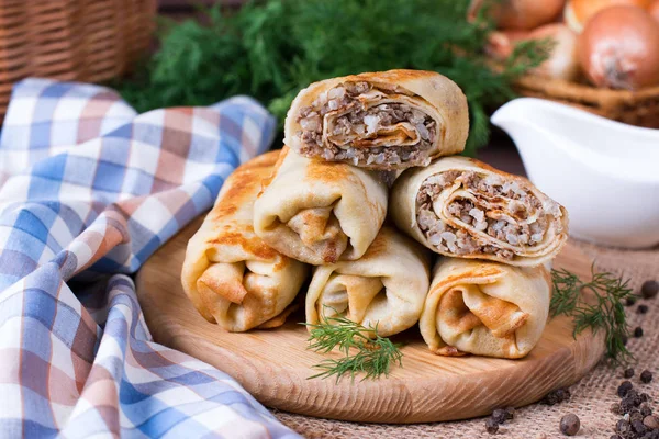 Crepes stuffed with minced meat and rice on a cutting board on a wooden table — Stock Photo, Image