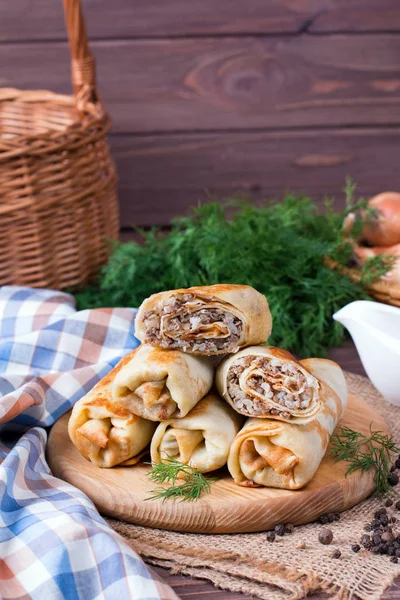 Crepes stuffed with minced meat and rice on a cutting board on a wooden table — Stock Photo, Image