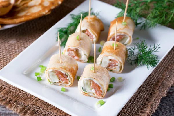 Rollos de panqueques finos con salmón ahumado y queso crema en el plato — Foto de Stock