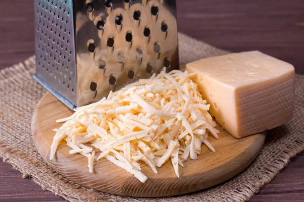 Queso rallado en una tabla de cortar de madera — Foto de Stock