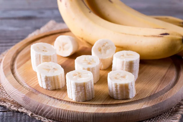 Tranches d'une banane sur une planche à découper sur une table en bois — Photo