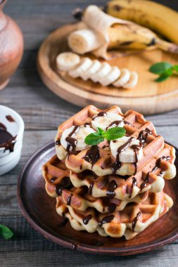 Çikolata şurubu ve muz dilimi ahşap arka plan üzerinde bir plaka üzerinde gözleme