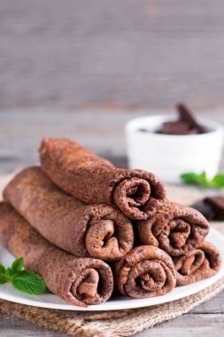 Ahşap zemin, krep üzerine bir plaka üzerinde ince çikolatalı krep haddelenmiş