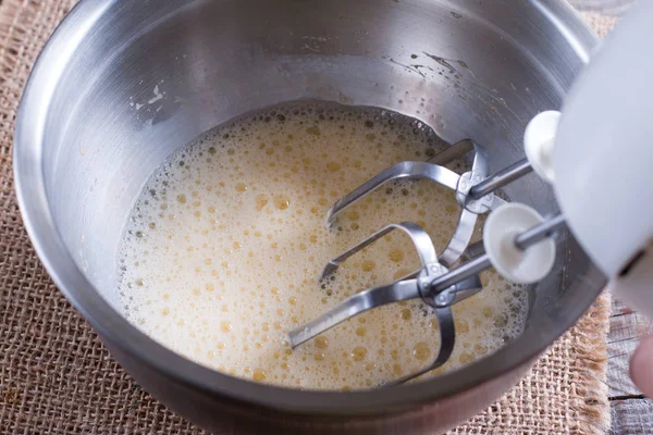 Cozinhar, bater ovos com batedor elétrico na tigela — Fotografia de Stock