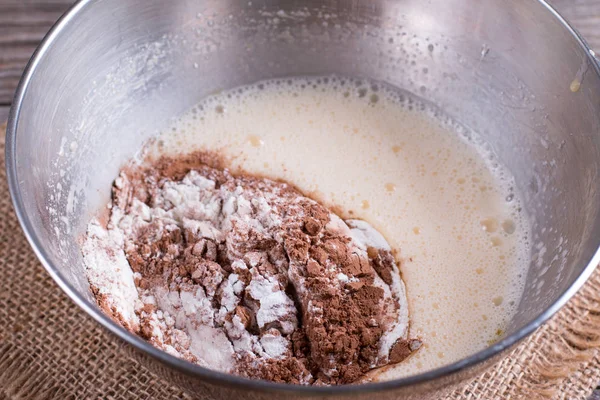Preparing a dough/batter for crepes or pancakes with wheat flour and cocoa in bowl, milk, eggs and oil — Stock Photo, Image