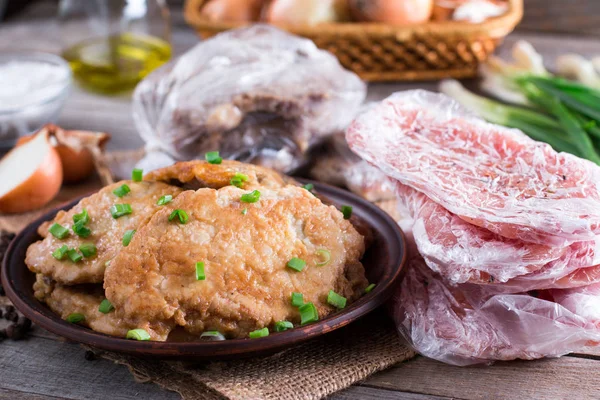 Свиной шницель в тарелке и замороженная свиная шея отбивает мясо — стоковое фото
