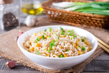 Bowl of fried rice, corn and egg on a wooden background. Healthy and light. clipart