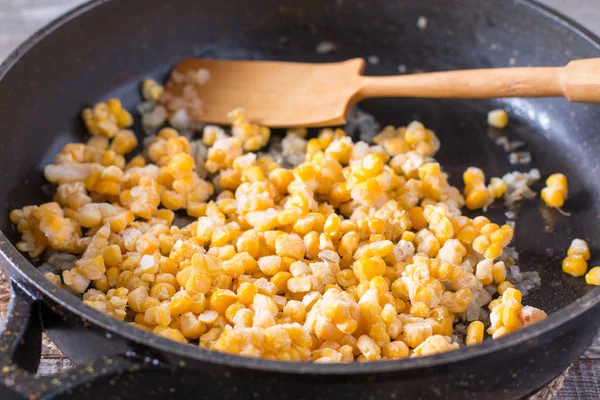 Frozen sweet corn in a frying pan on a wooden table — Stock Photo, Image