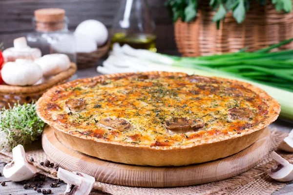 Koláč tradiční francouzský quiche s kuřecím masem a žampiony na dřevěný stůl — Stock fotografie