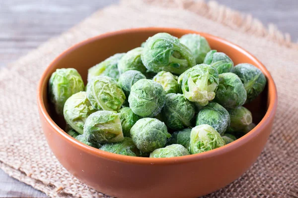 Frozen Brussels sprouts in a bowl on a wooden table — Stock Photo, Image