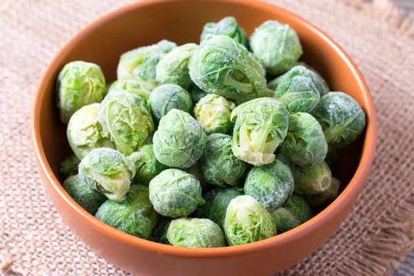 Frozen Brussels sprouts in a bowl on a wooden table — Stock Photo, Image