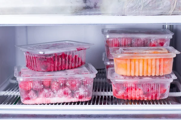 Frutas y bayas congeladas en un recipiente en el congelador —  Fotos de Stock