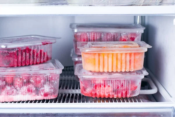 Frozen fruits and berries in a container in the freezer