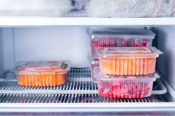 Замороженные фрукты и ягоды в контейнере в морозилке — стоковое фото