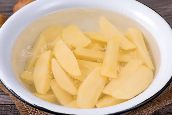 Gesneden aardappelen in water in een metaalkom — Stockfoto