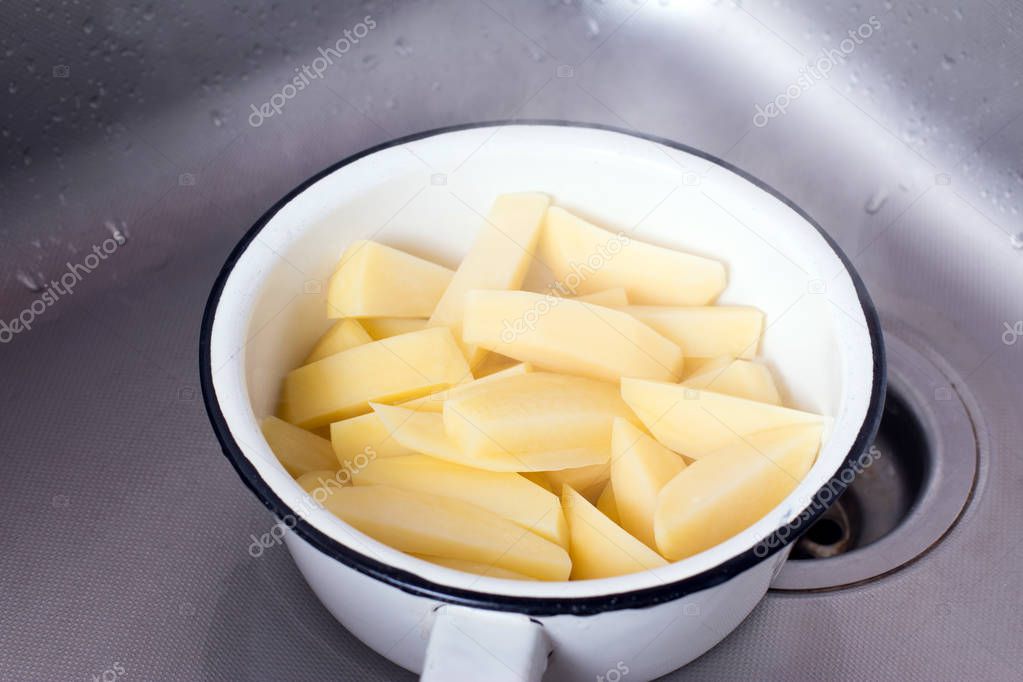Draining boiled potato slices in colander
