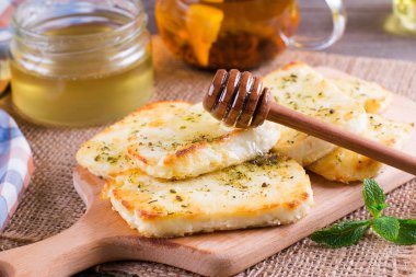 Grilled haloumi cheese with herbs on a cutting board clipart