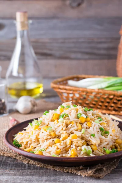 Азиатский жареный рис с яйцами и кукурузой на деревянном фоне — стоковое фото