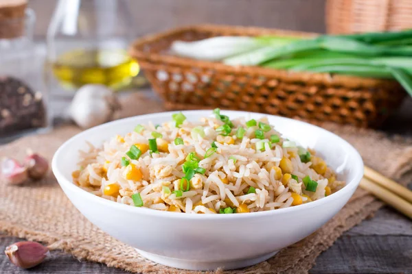 Arroz frito asiático com ovos e milho no prato em fundo de madeira — Fotografia de Stock