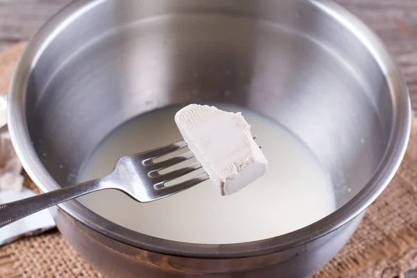 在一碗牛奶的叉子上的酵母 — 图库照片