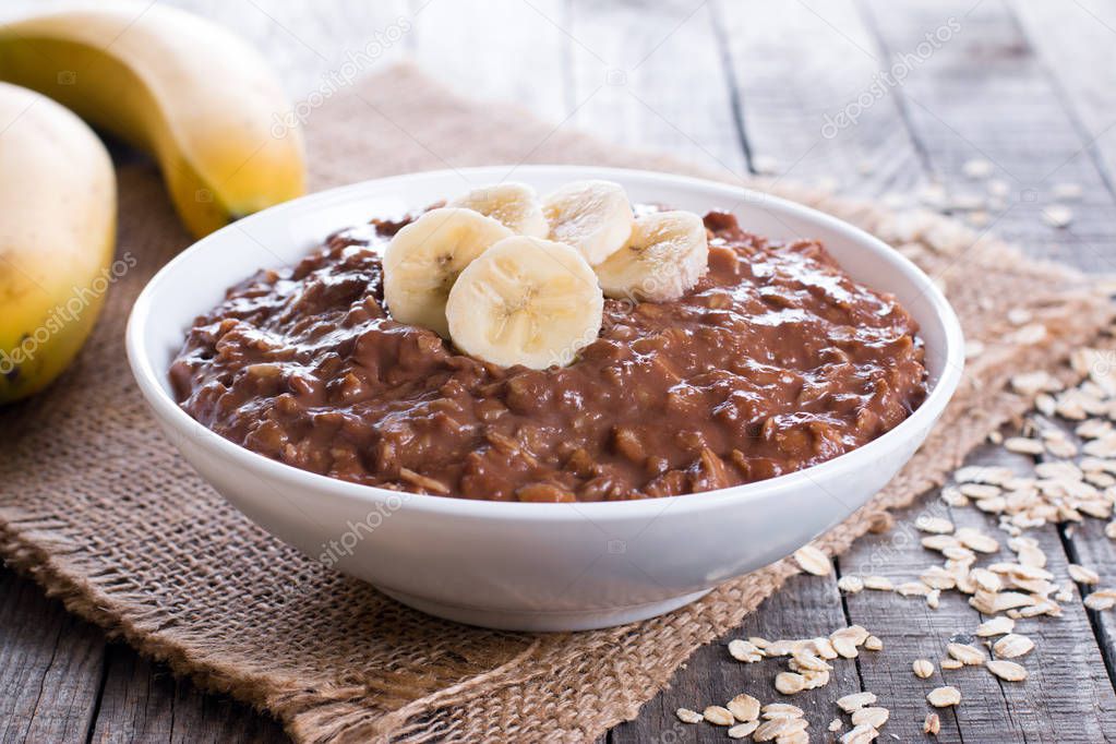 Chocolate oatmeal with banana in white bowl for breakfast