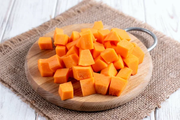 Cubos de calabaza sobre tabla de cortar sobre mesa de madera — Foto de Stock