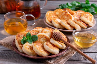 Cottage cheese pancakes, syrniki with honey on a plate on wooden background