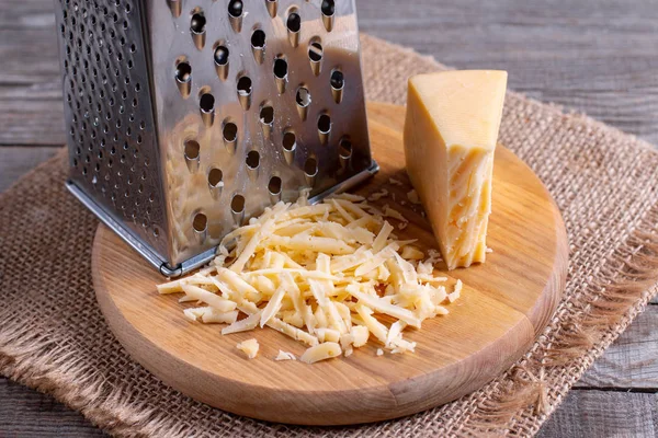 Geraspte kaas op een snijplank op een houten tafel — Stockfoto