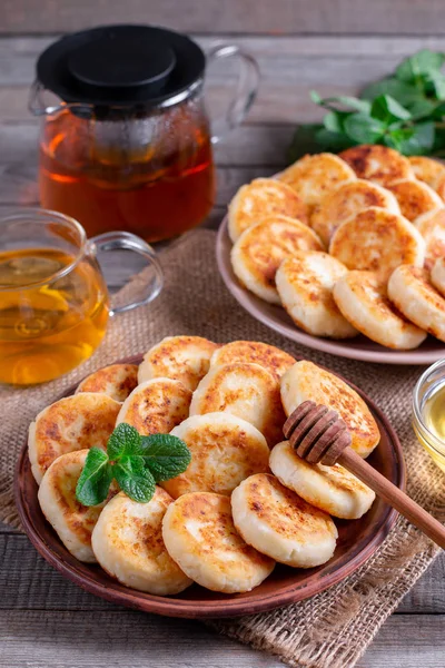 Panquecas de queijo de casa de campo, syrniki com mel em uma chapa no fundo de madeira — Fotografia de Stock