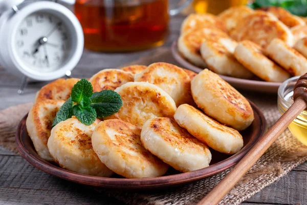 Оладьи с сыром, сироники с медом на тарелке на деревянном фоне — стоковое фото