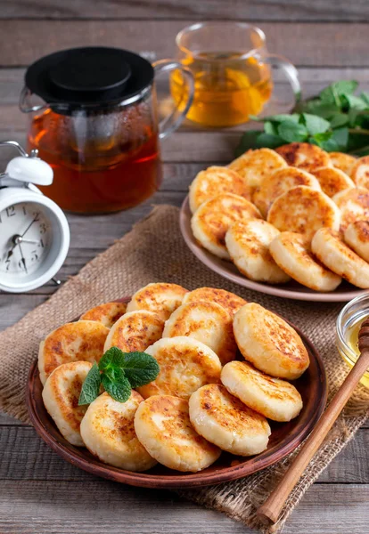 Panqueques de queso de cabaña, syrniki con miel en un plato sobre fondo de madera —  Fotos de Stock