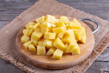 Sliced potatoes on cutting board on wooden background
