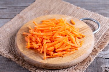 Sliced carrots on cutting board on wooden background
